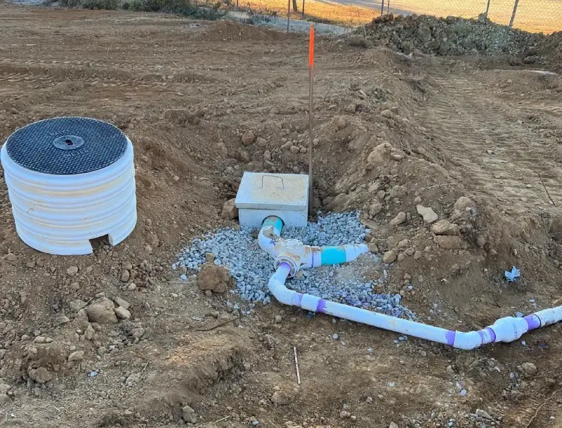 A pipe laying in the ground next to a box.