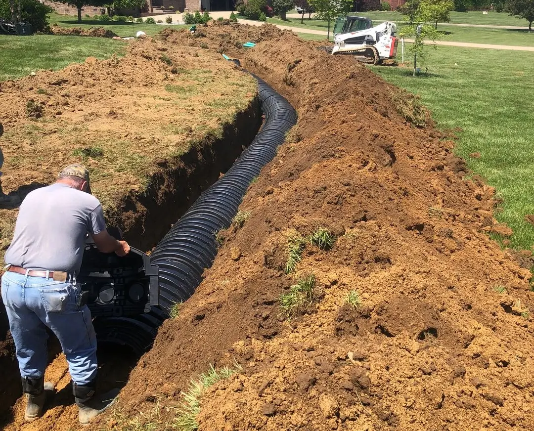 A man is working on the side of a trench.