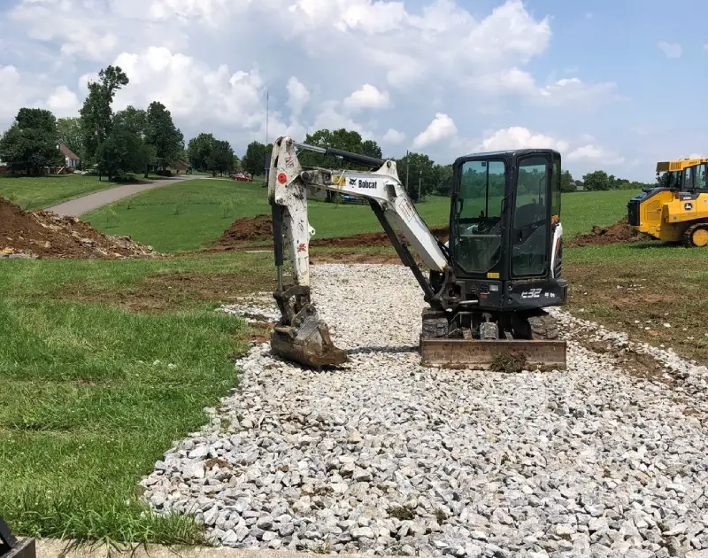 A small white and black excavator on gravel